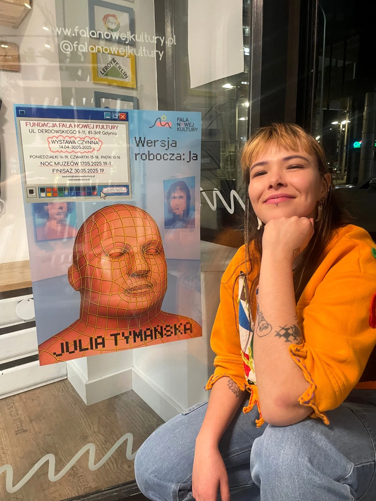 Julia Tymańska przy plakacie wystawy Wersja robocza: Ja